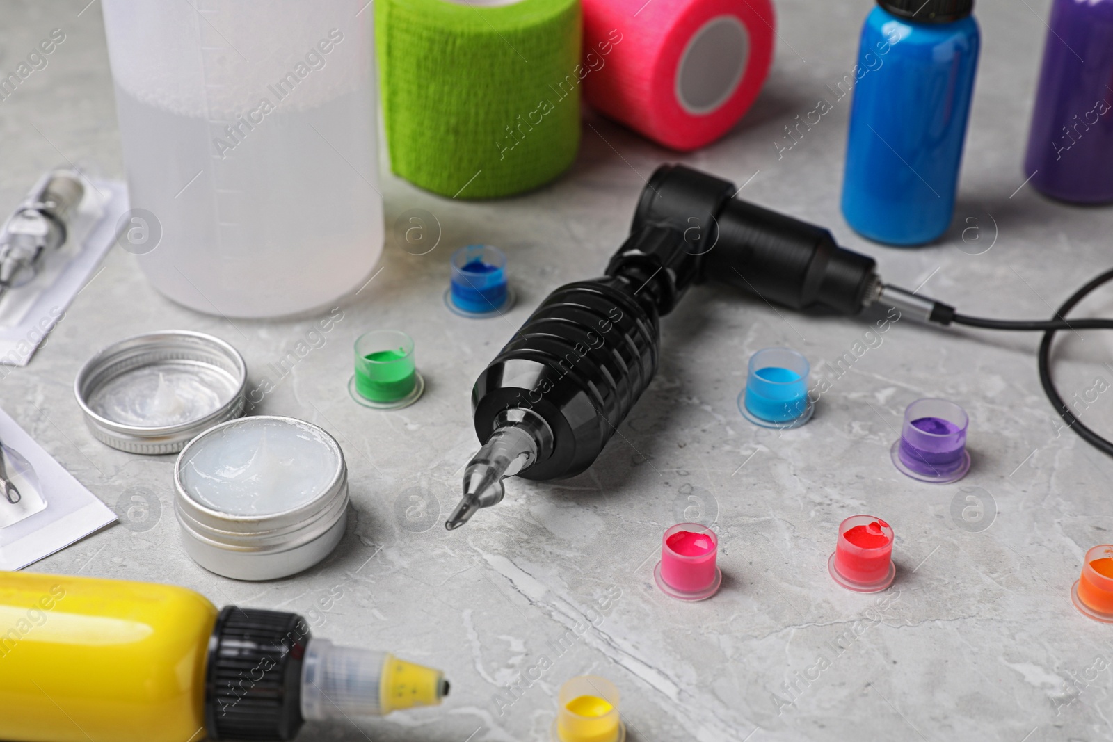 Photo of Tattoo machine and professional tools on light grey table