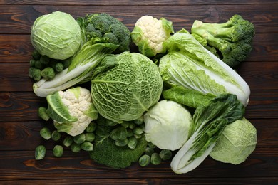 Photo of Many different types of fresh cabbage on wooden table, flat lay