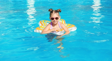 Photo of Little girl with inflatable ring in swimming pool on sunny day