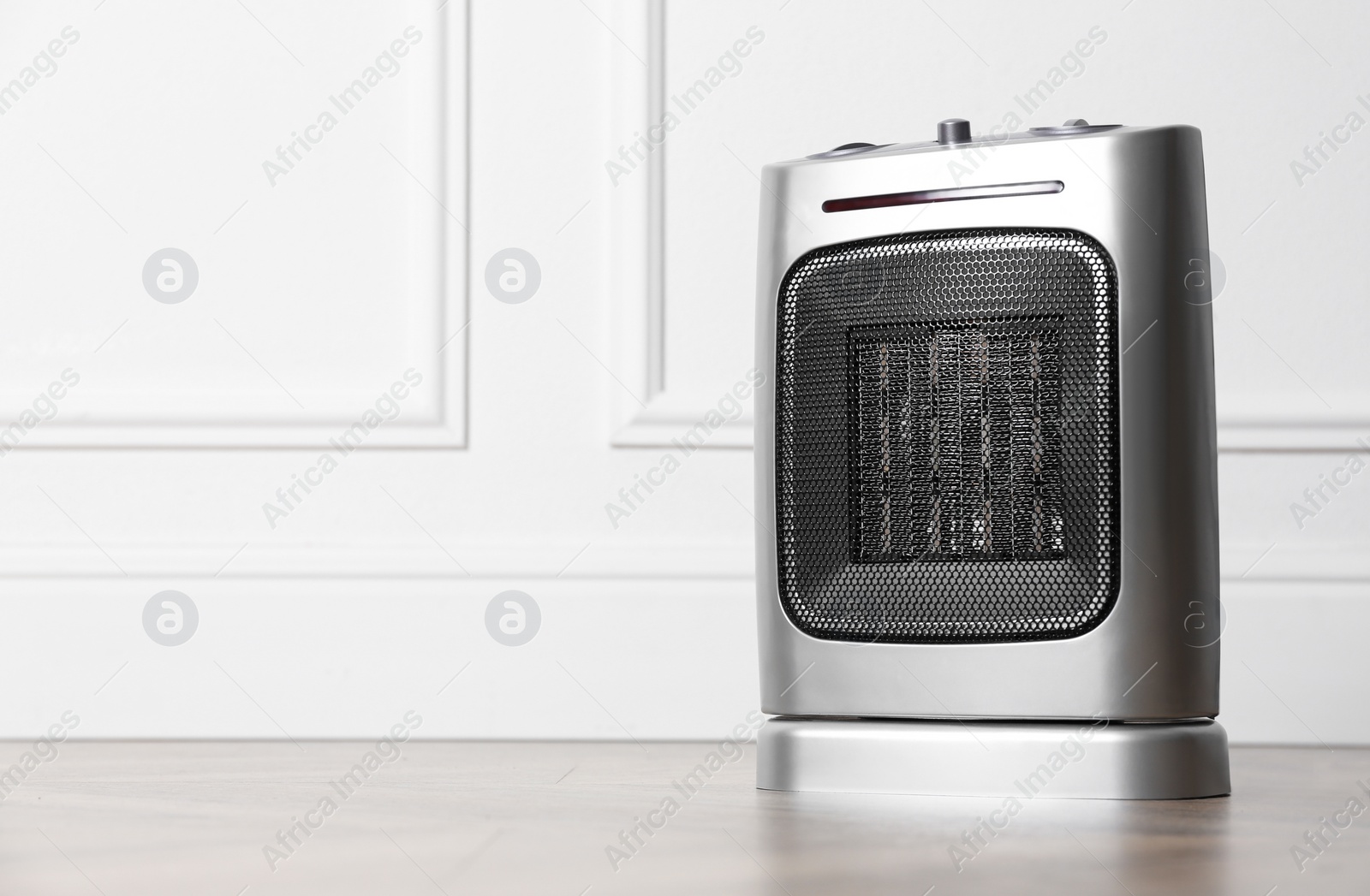 Photo of Modern electric fan heater on floor in room, space for text