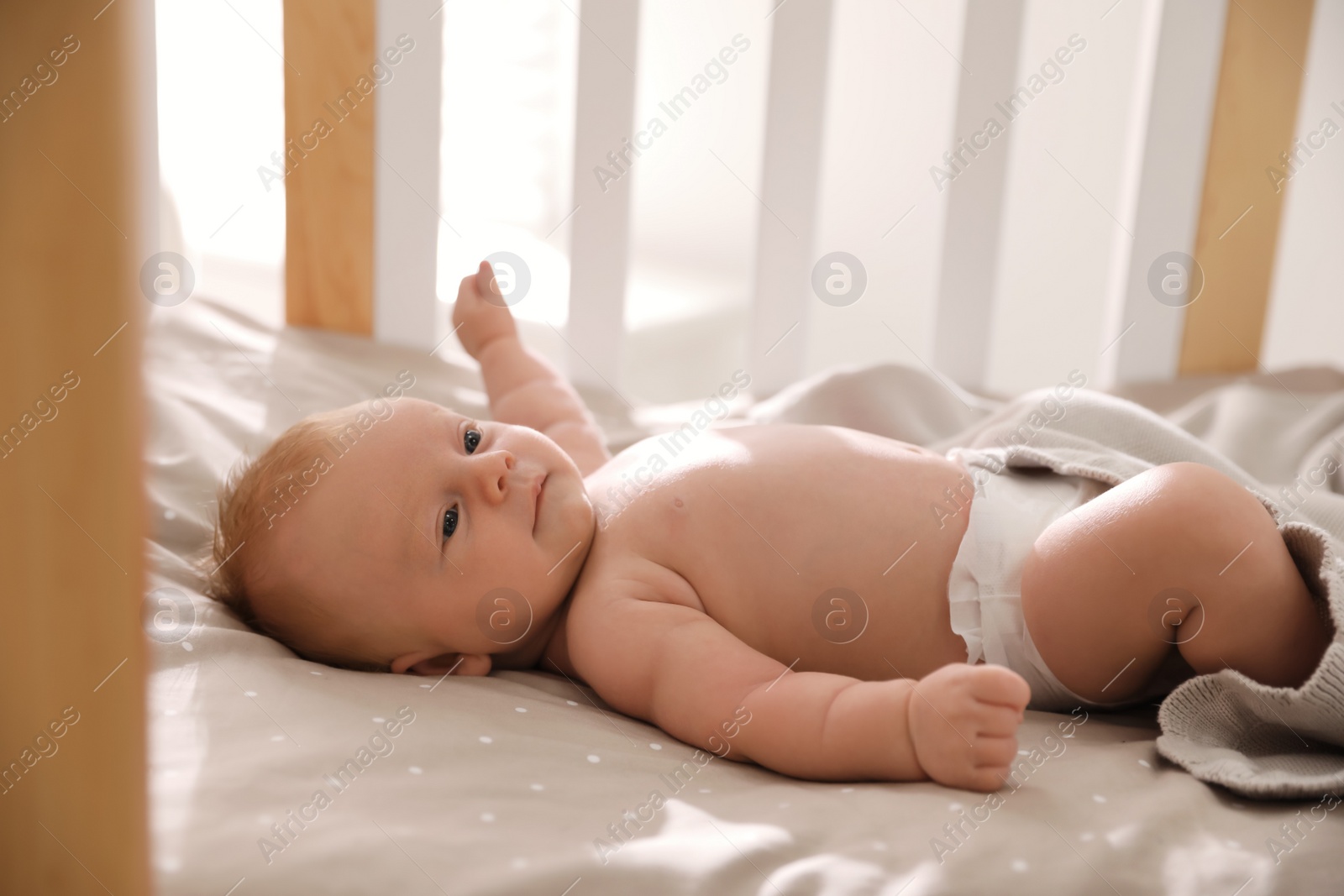 Photo of Cute little child lying in cot. Healthy baby