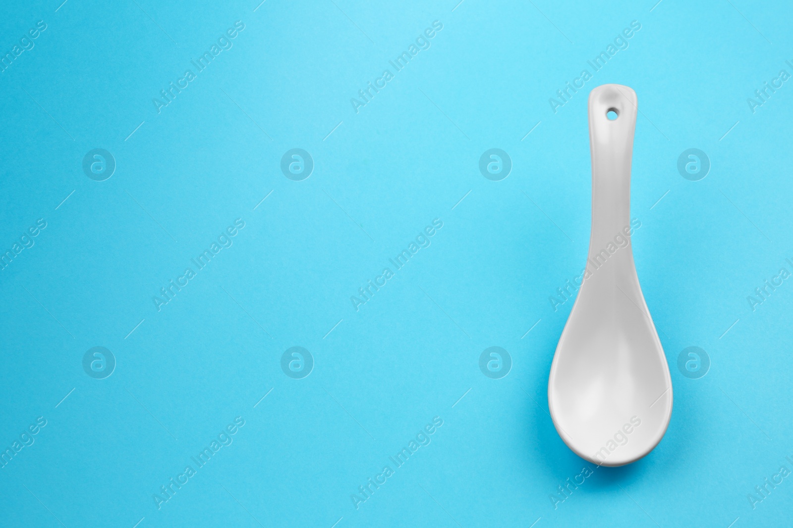 Photo of Clean empty miso spoon on blue background, space for text