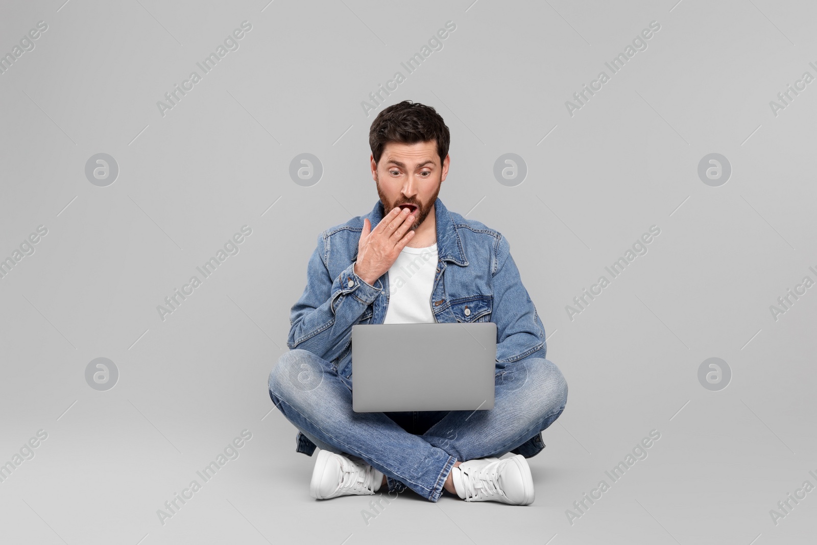 Photo of Emotional man with laptop on light grey background