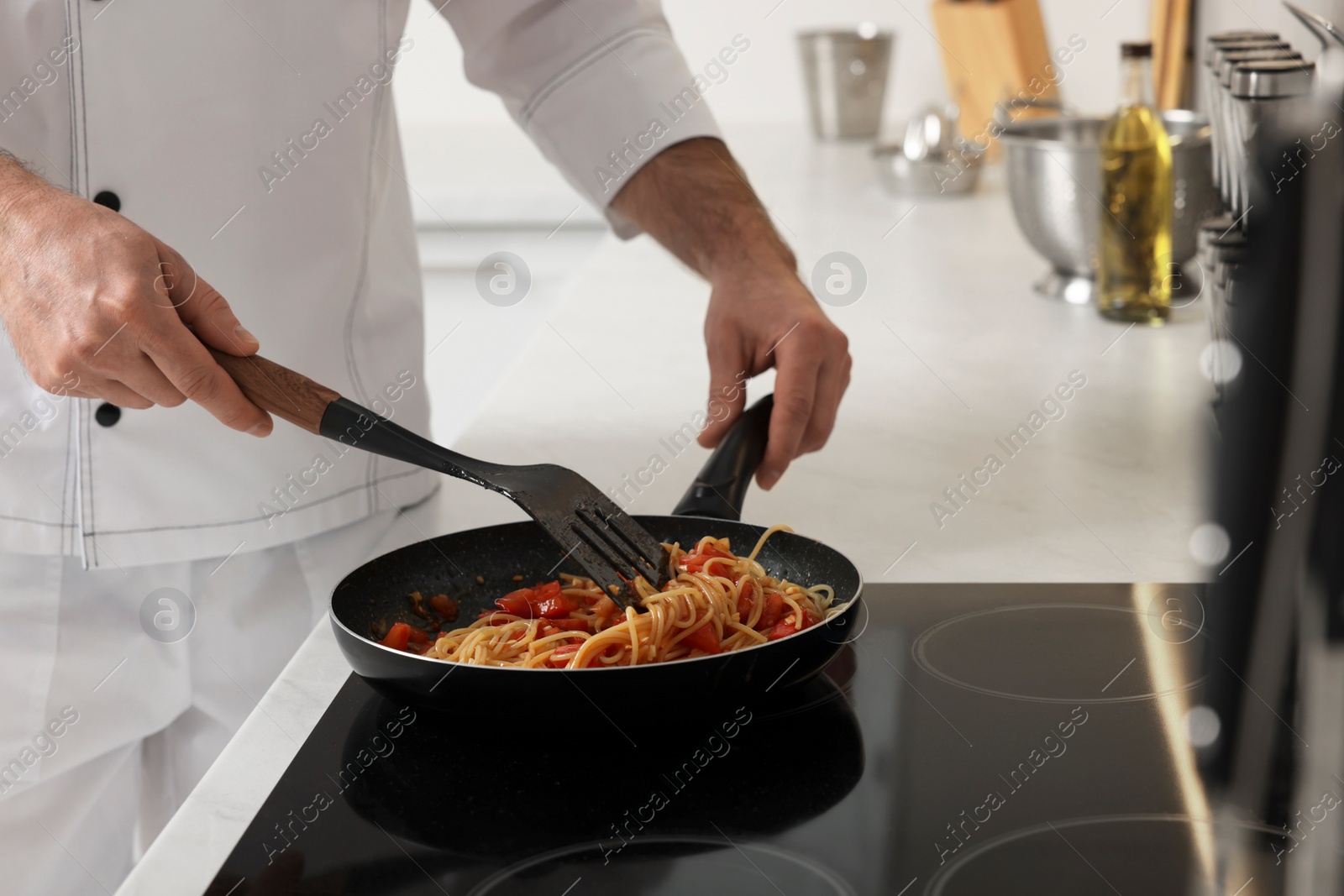 Photo of Professional chef cooking delicious pasta on stove in kitchen, closeup