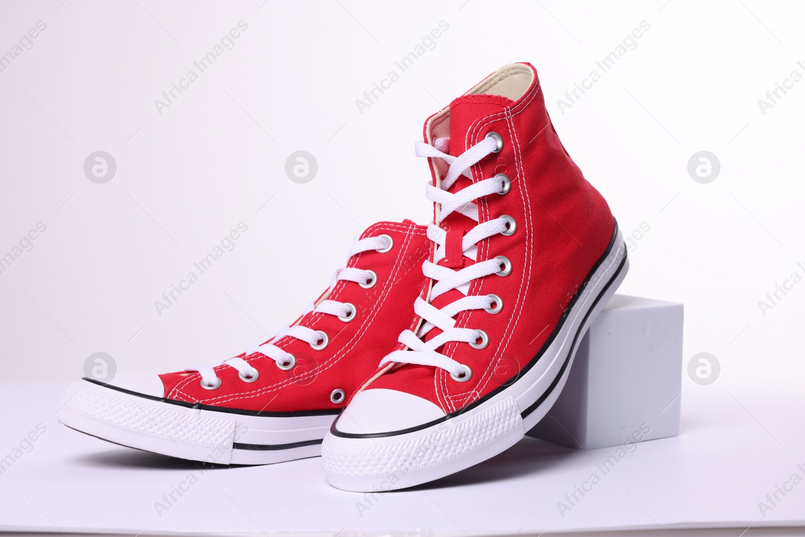 Photo of Pair of new red stylish high top plimsolls on white background