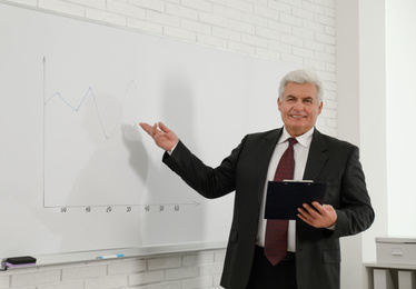 Photo of Senior business trainer near whiteboard in office