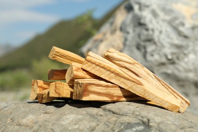 Photo of Many palo santo sticks on stone surface in high mountains, closeup