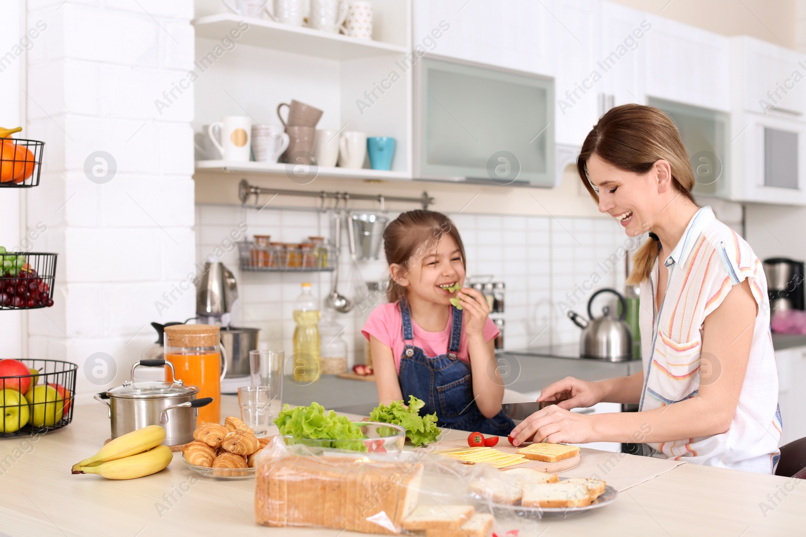 Photo of Housewife with her daughter preparing dinner on kitchen
