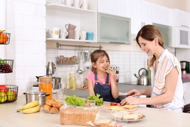 Housewife with her daughter preparing dinner on kitchen