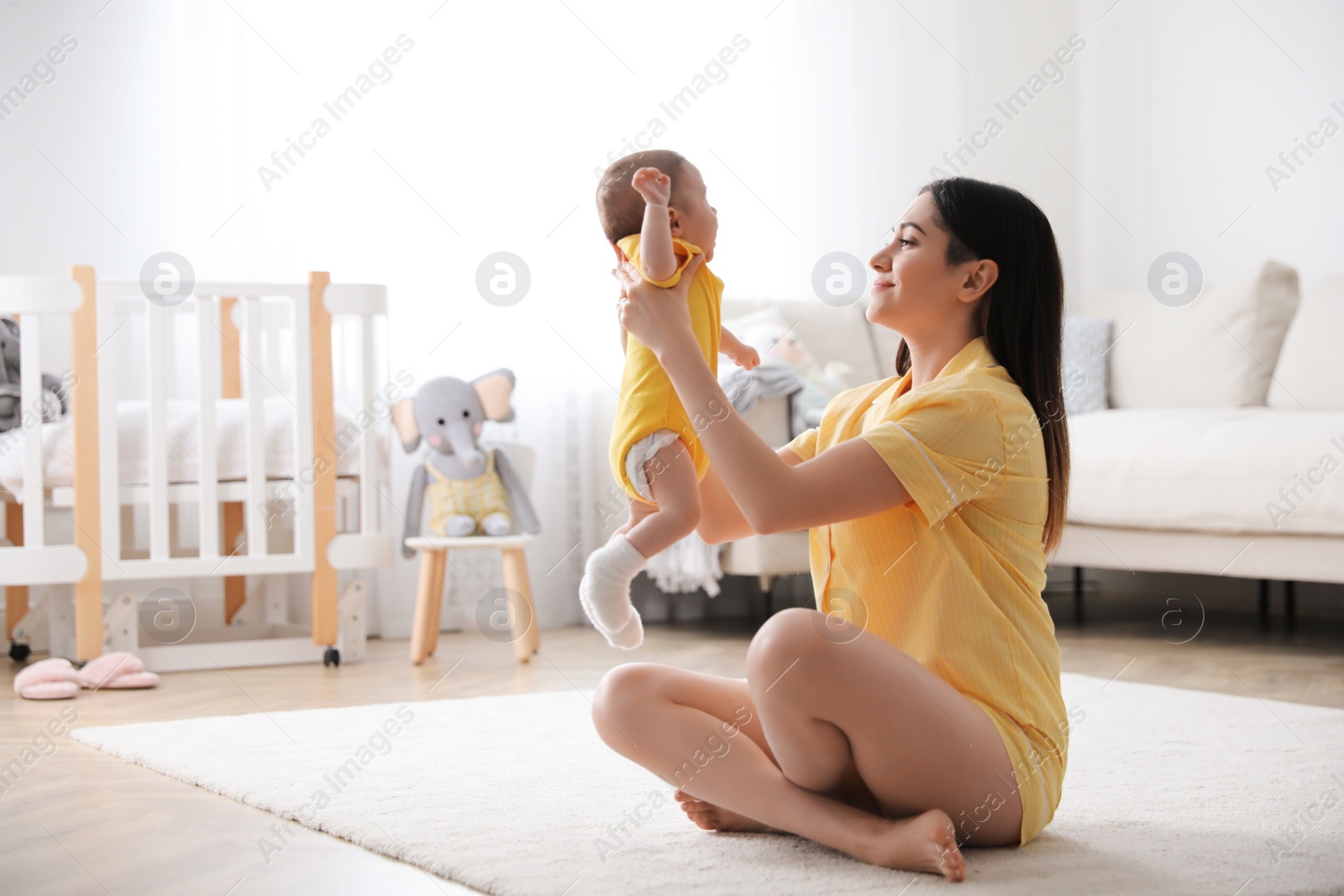 Photo of Young woman with her cute baby at home, space for text