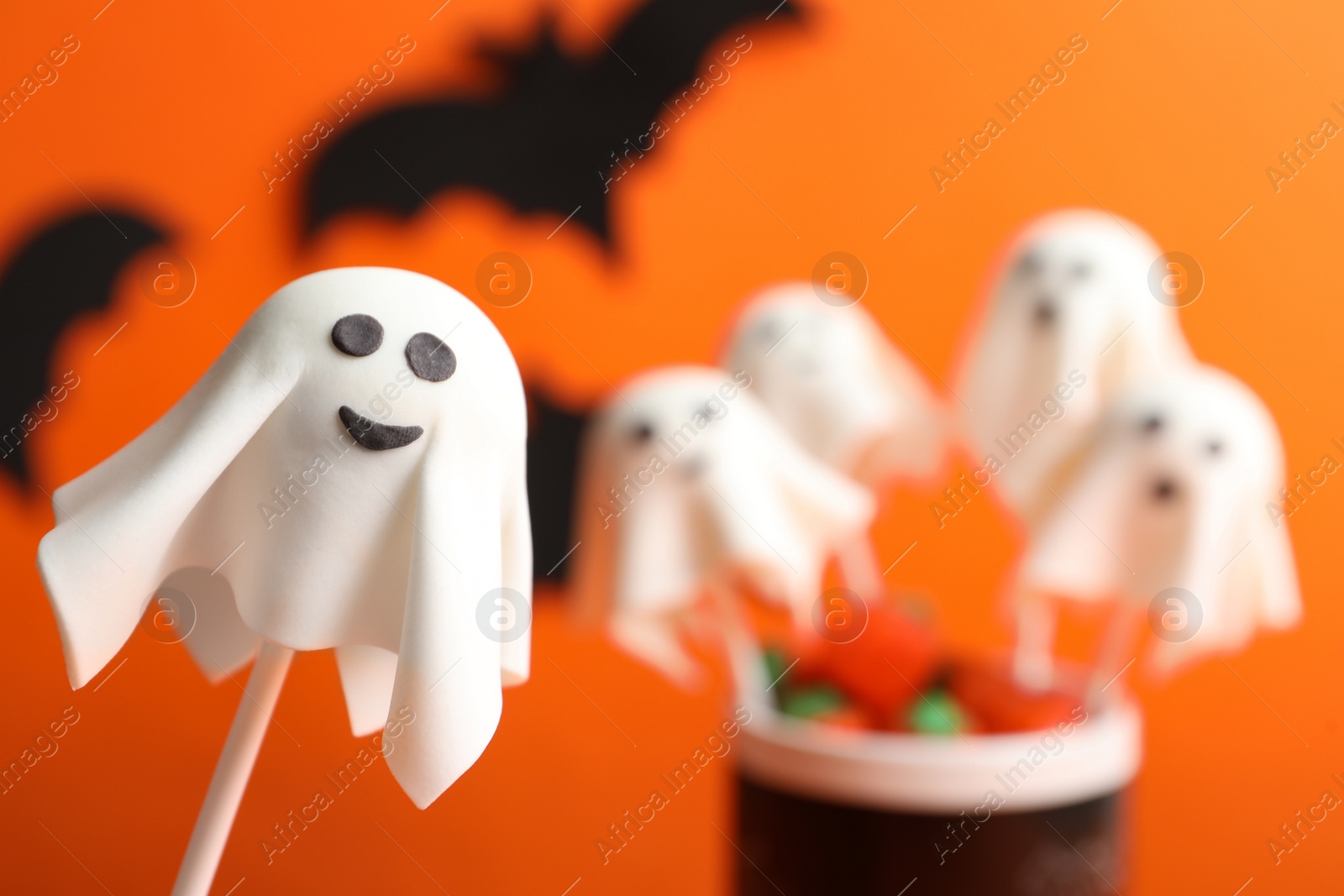 Photo of Delicious Halloween themed cake pops on orange background, closeup. Space for text
