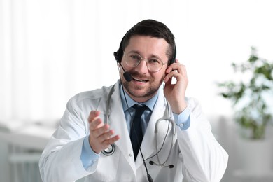 Photo of Smiling doctor in headset having online consultation in clinic