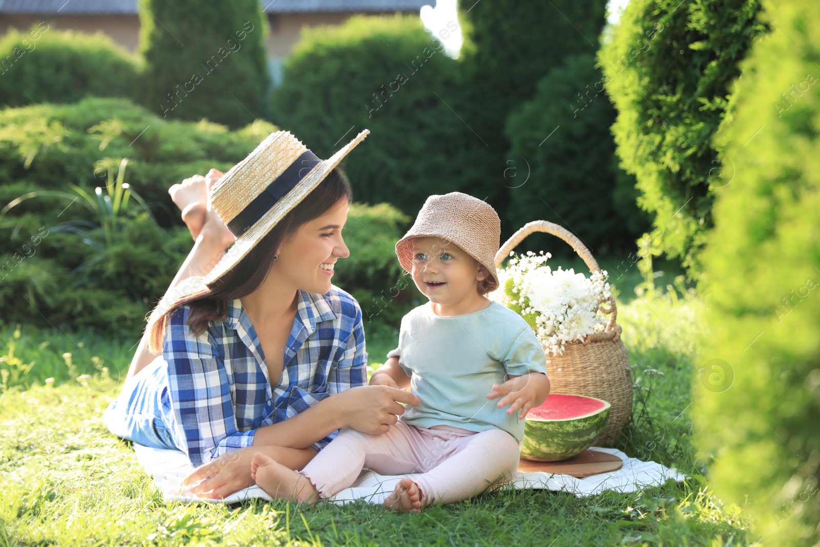 Photo of Mother with her baby daughter having picnic in garden on sunny day