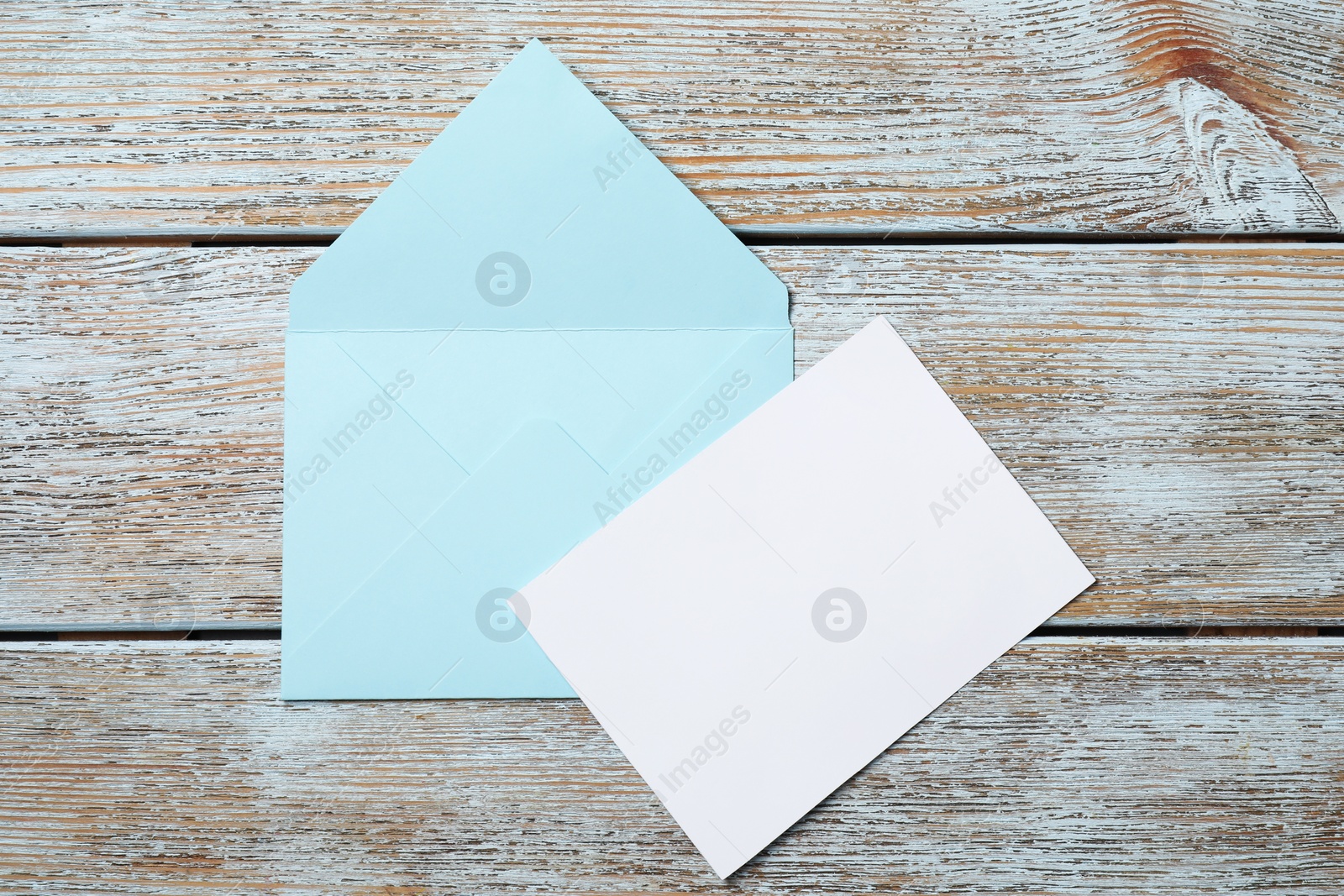 Photo of Blank sheet of paper and letter envelope on wooden rustic table, top view. Space for text