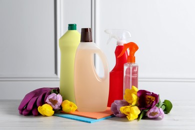 Spring cleaning. Detergents, flowers and tools on white wooden table