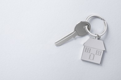 Photo of Key with keychain in shapehouse on light background, top view. Space for text