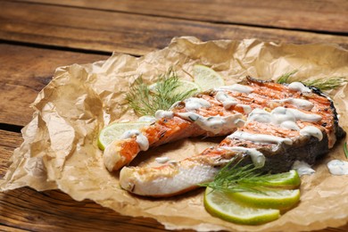 Tasty salmon steak with sauce, citrus slices and dill on wooden table, closeup