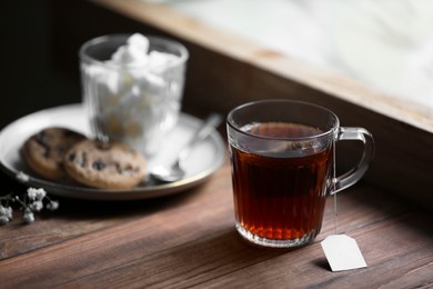 Photo of Cup of freshly brewed tea on wooden table, space for text