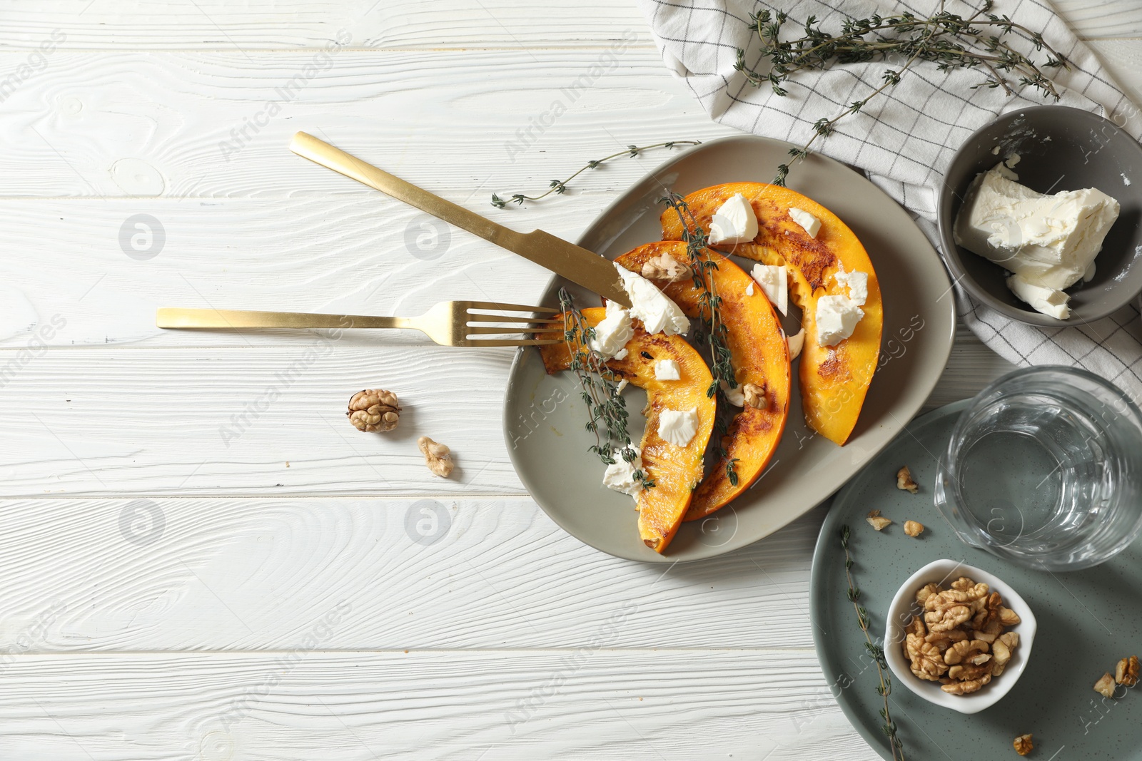 Photo of Delicious pumpkin slices served with thyme and cheese on white wooden table, flat lay