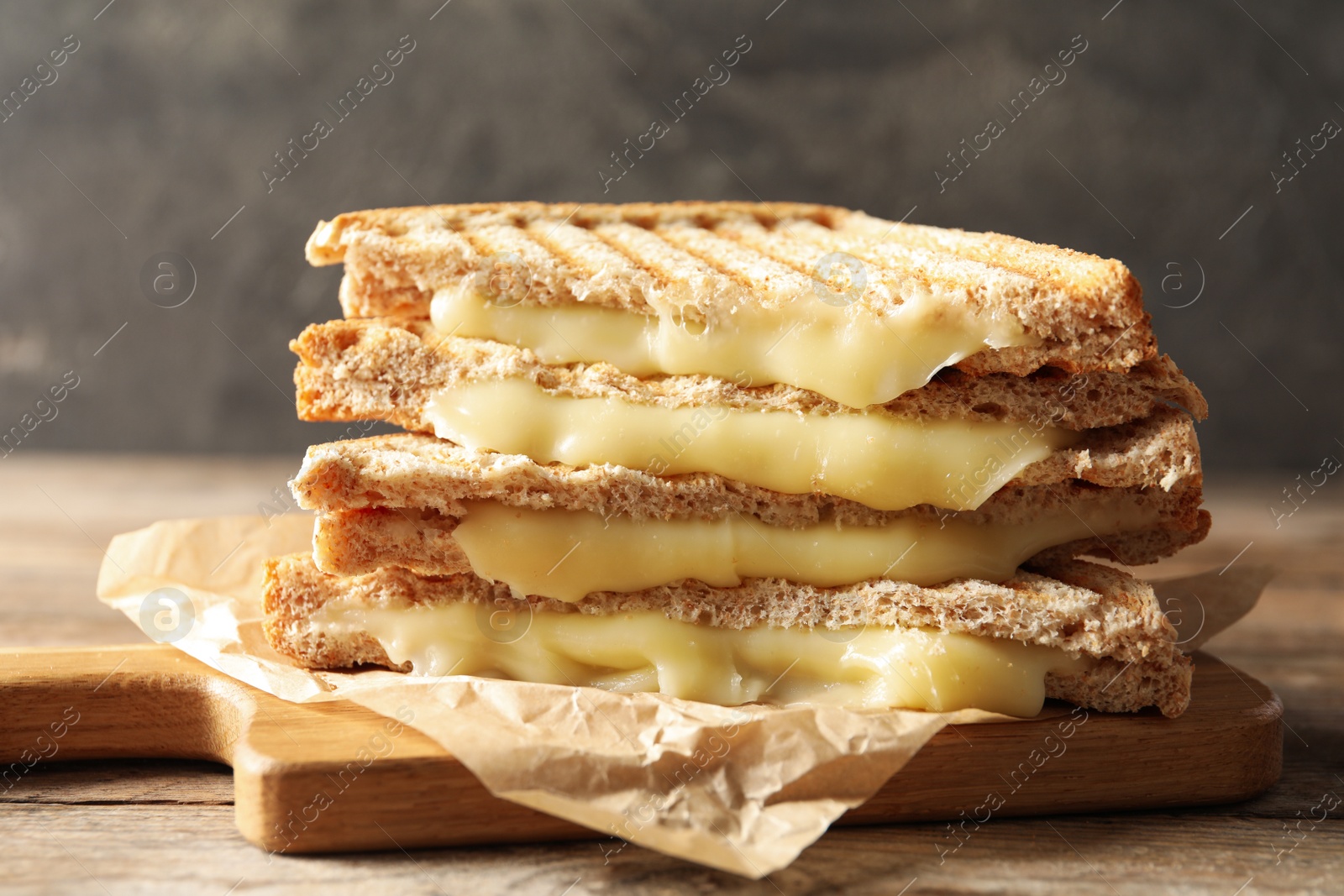 Image of Tasty toast sandwiches with cheese on wooden table