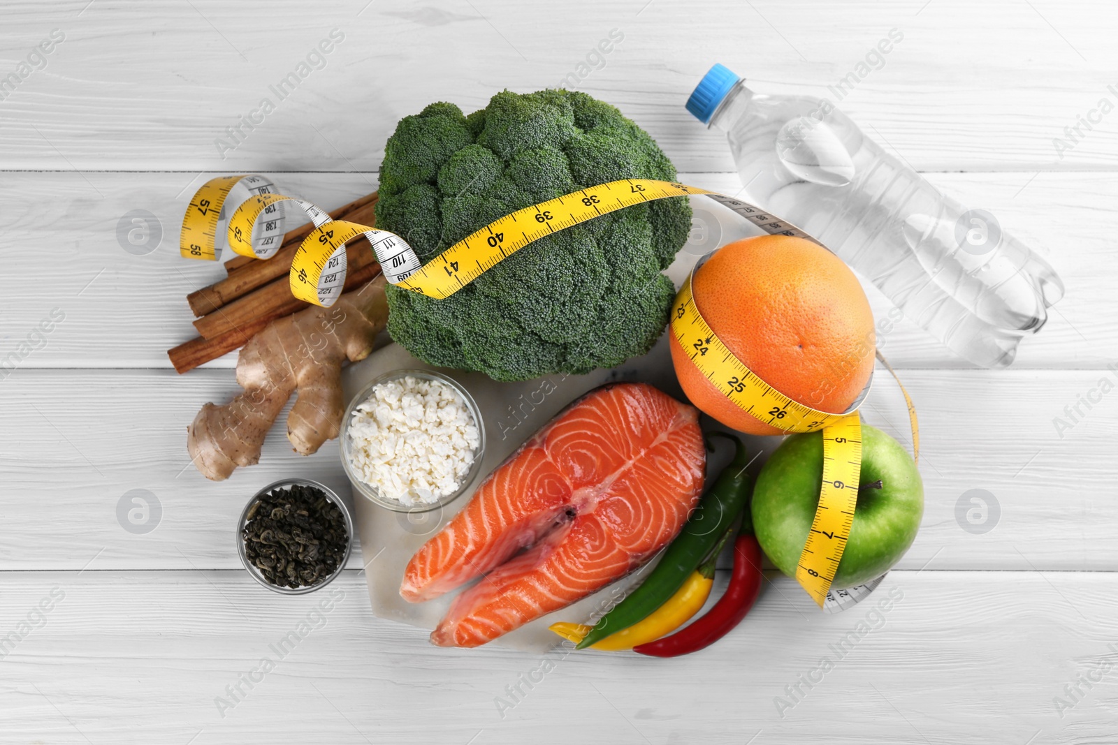 Photo of Metabolism. Different food products and measuring tape on white wooden table, flat lay