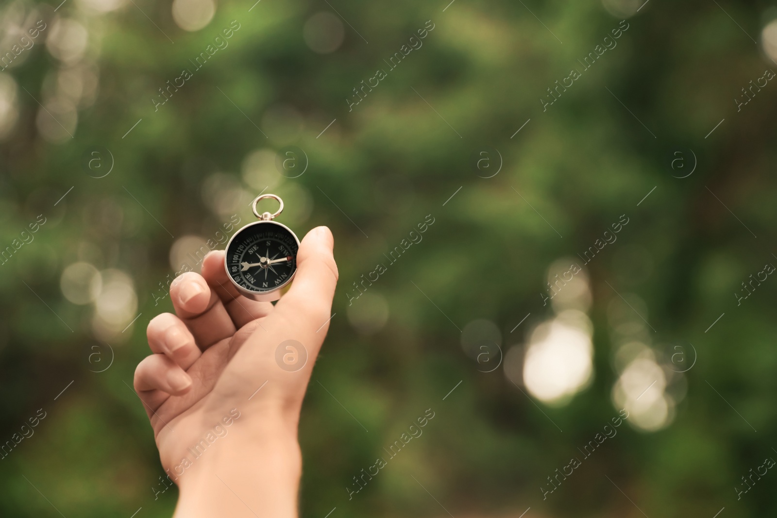 Photo of Woman checking modern compass in wilderness, closeup with space for text