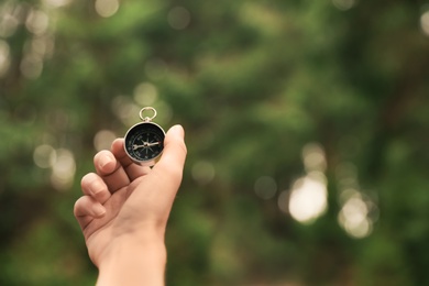 Photo of Woman checking modern compass in wilderness, closeup with space for text