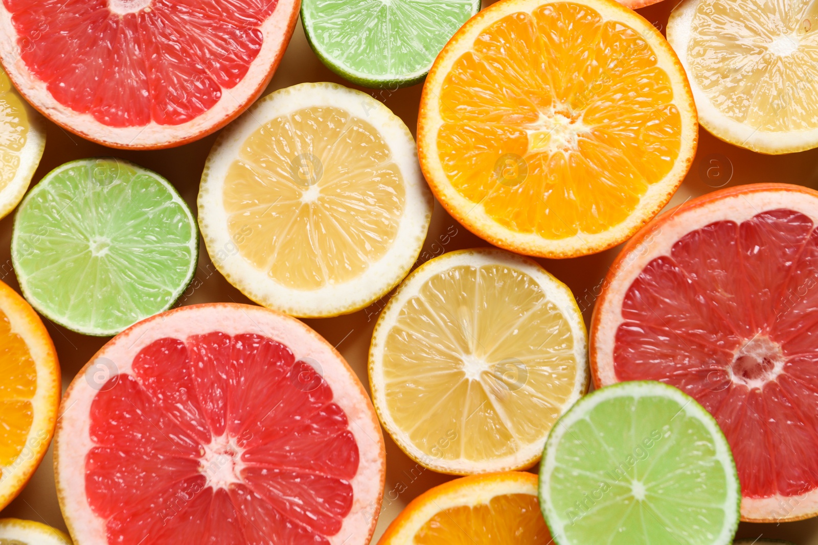 Photo of Different cut citrus fruits on beige table, flat lay