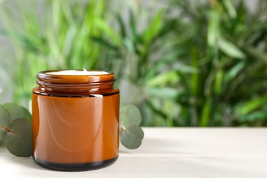 Photo of Jar of hand cream and eucalyptus branch on white table, space for text