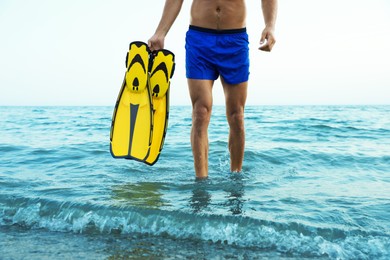 Man with flippers walking out of sea water, closeup