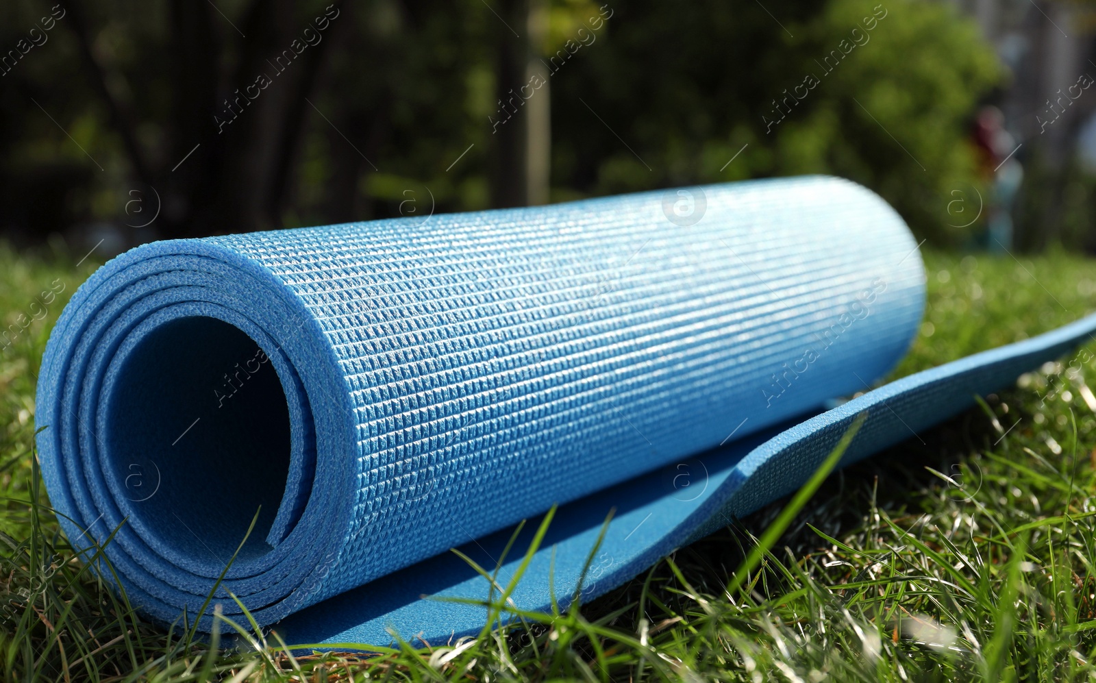 Photo of Bright exercise mat on fresh green grass outdoors