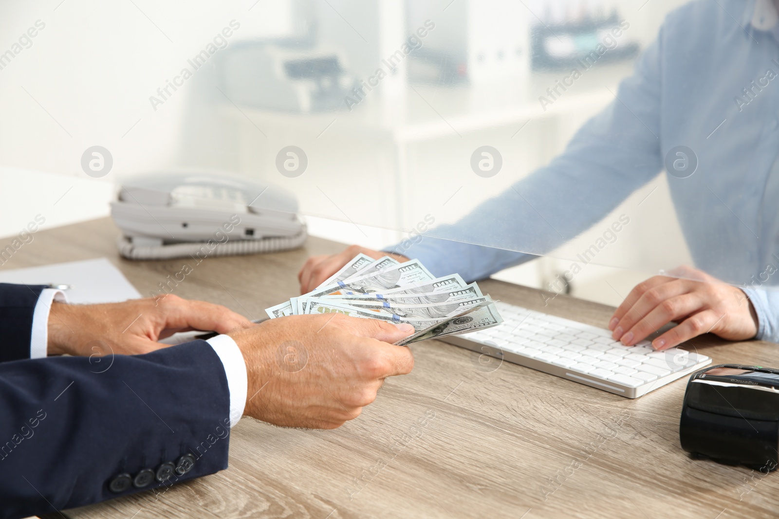 Photo of Man giving money to teller at cash department window, closeup