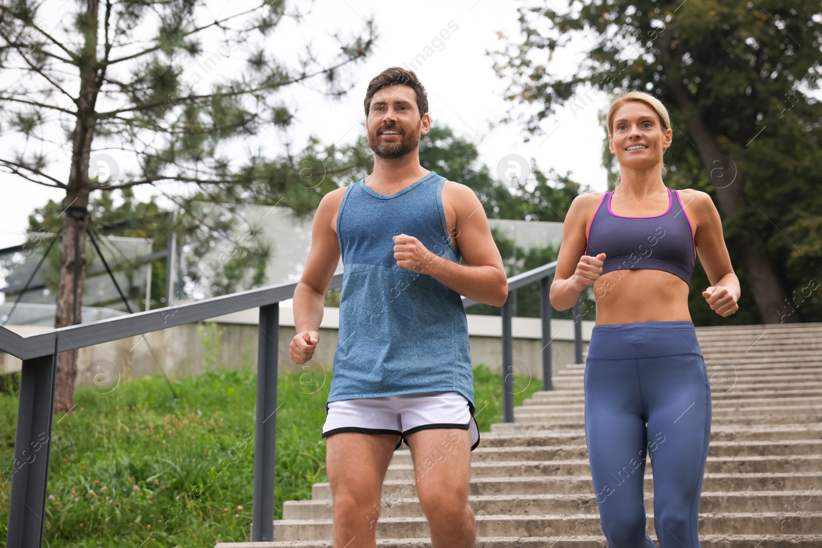 Photo of Healthy lifestyle. Happy couple running down stairs outdoors