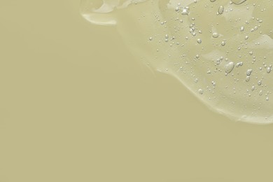 Photo of Transparent cleansing gel on pale olive background, top view with space for text. Cosmetic product