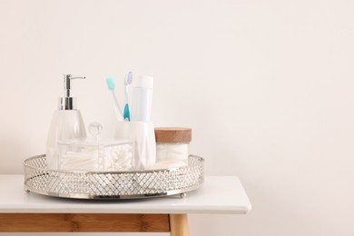 Photo of Different bath accessories and personal care products on table near white wall, space for text