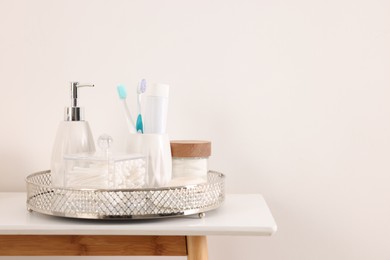 Different bath accessories and personal care products on table near white wall, space for text