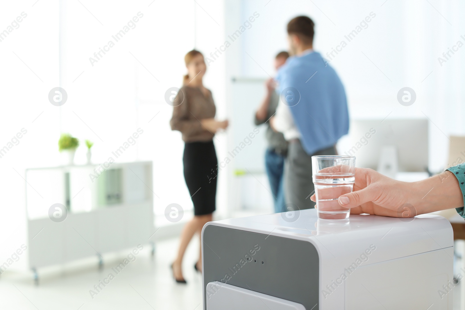 Photo of Office employee with glass near water cooler at workplace, closeup. Space for text