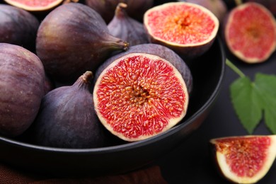 Photo of Bowl with fresh ripe figs on black table, closeup