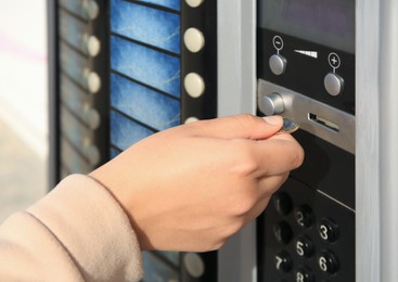 Image of Using coffee vending machine. Woman inserting coin to pay for drink, closeup