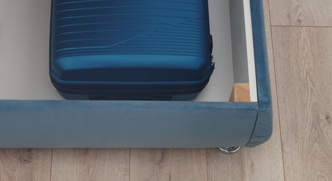 Storage drawer under bed with blue suitcase indoors, above view