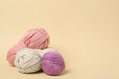 Photo of Soft woolen yarns on beige background, space for text