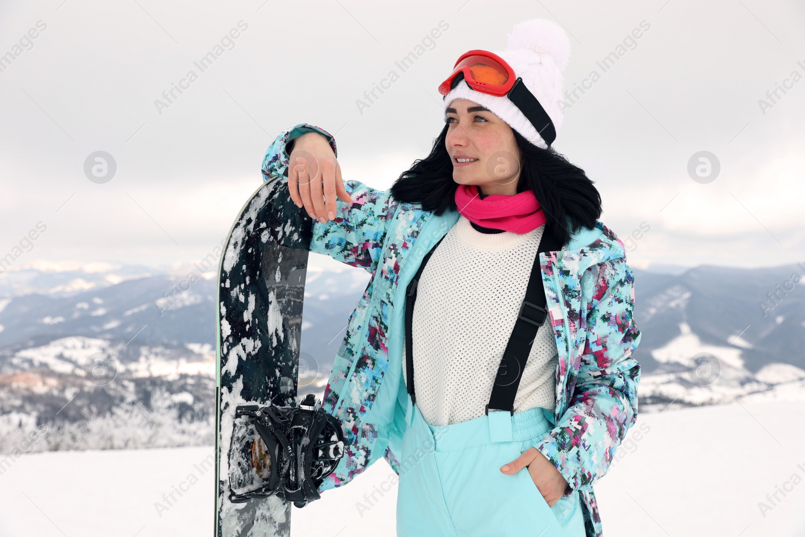 Photo of Beautiful young woman with snowboard on snowy hill. Winter vacation