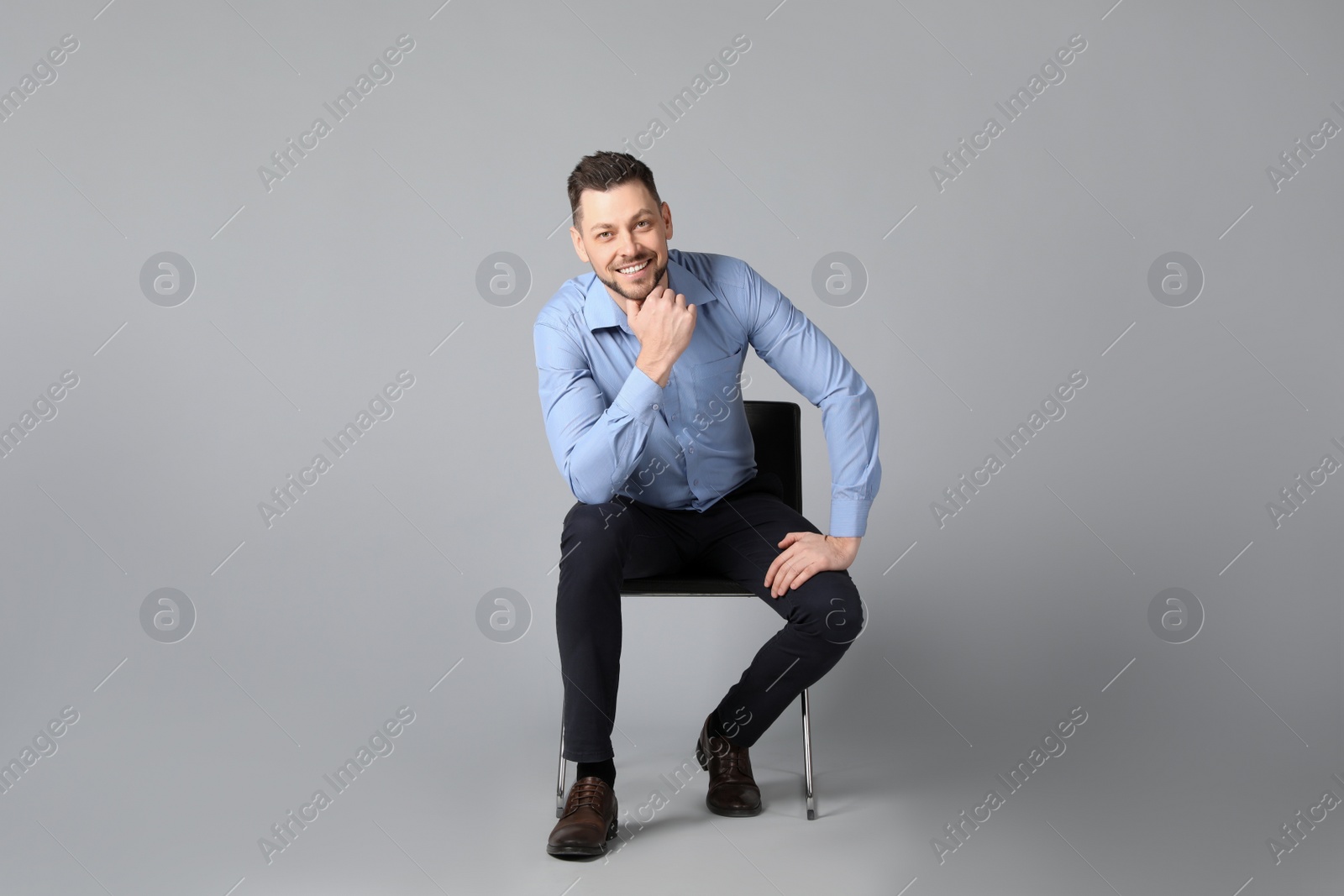 Photo of Handsome man sitting in office chair on grey background