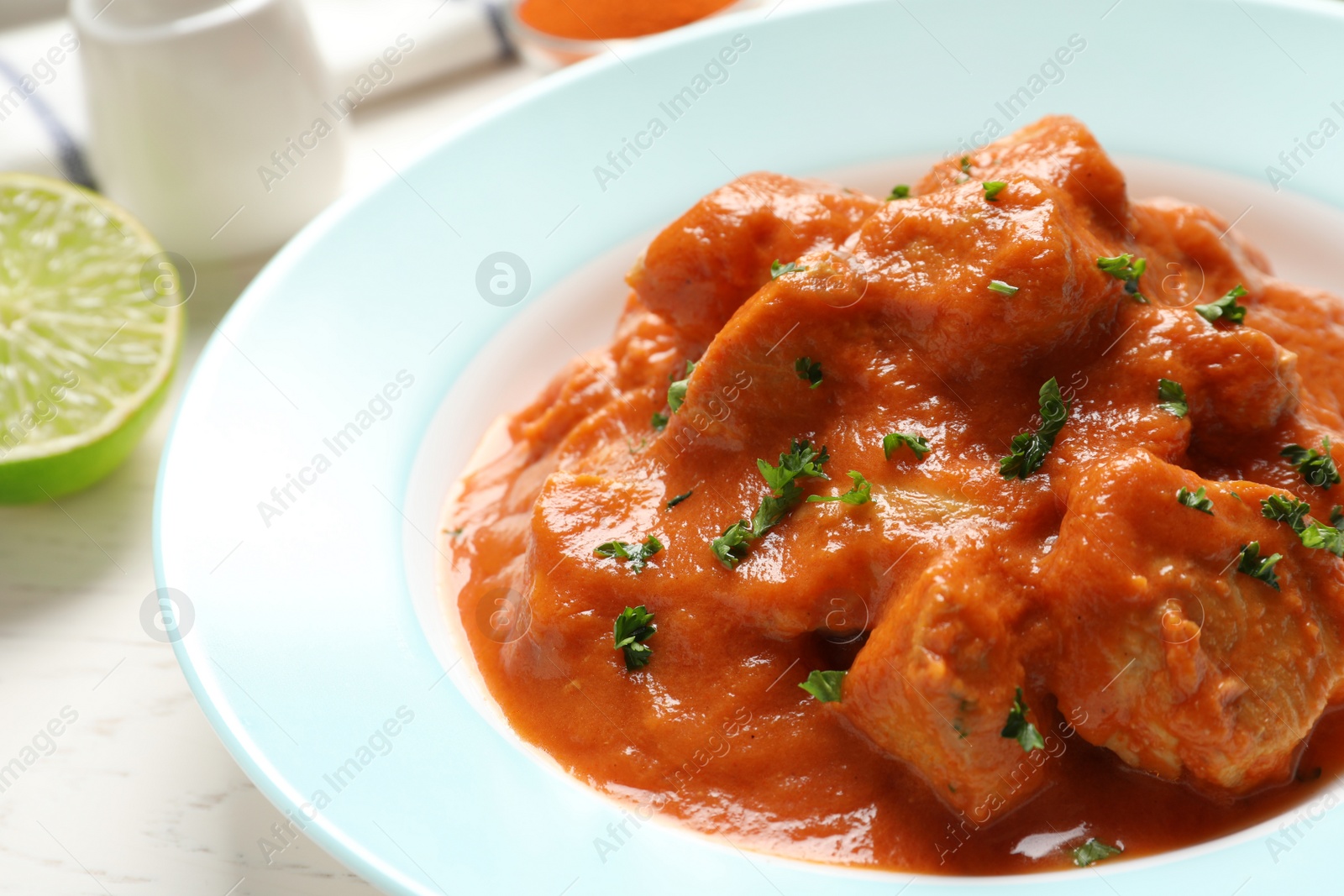 Photo of Plate of delicious butter chicken on table, closeup. Traditional Murgh Makhani dish