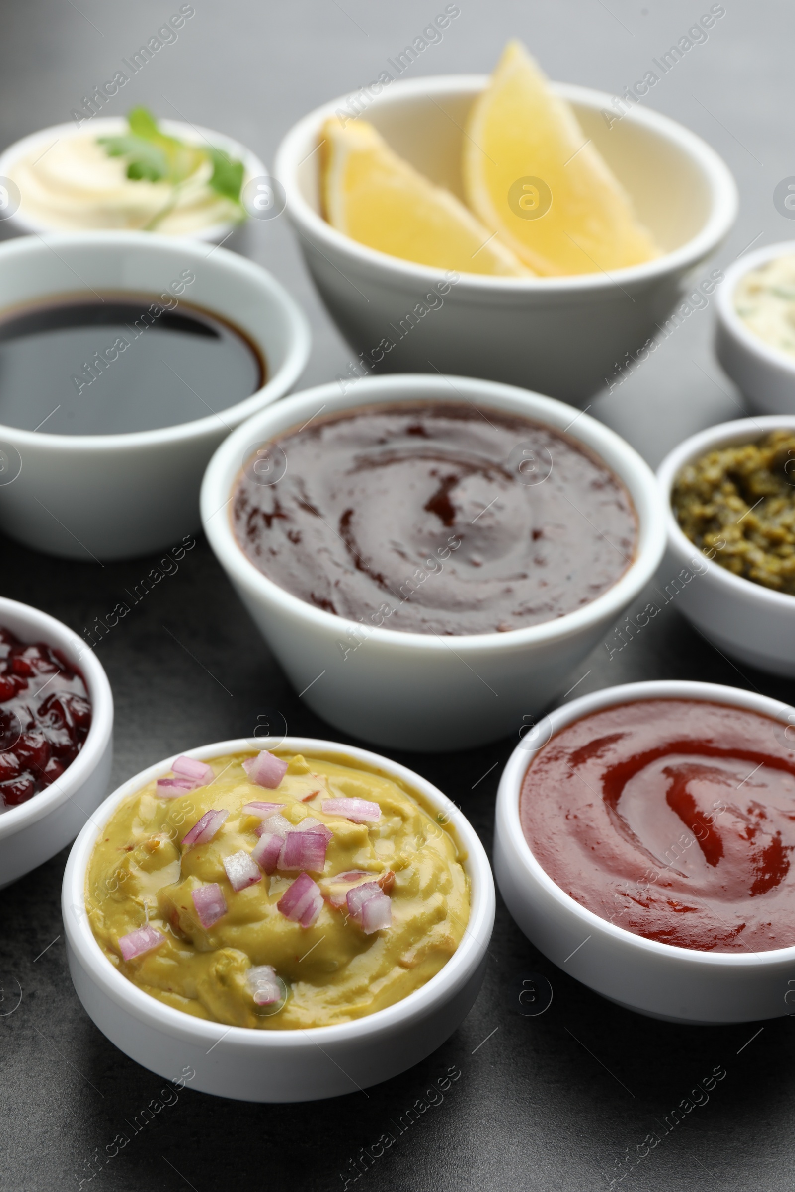 Photo of Different tasty sauces in bowls on grey table
