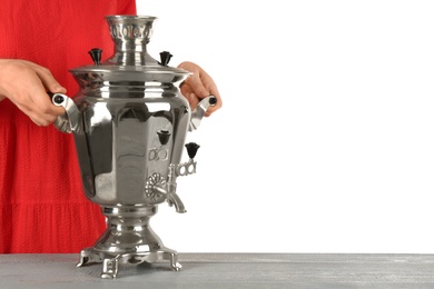 Photo of Woman holding traditional Russian samovar on grey table against white background, closeup. Space for text