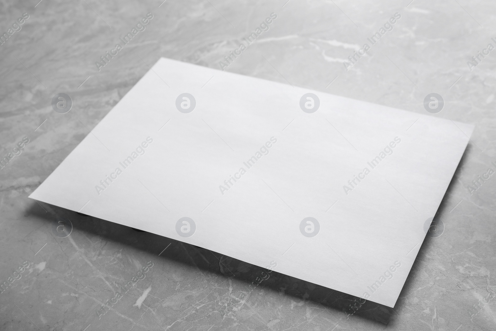 Photo of Blank paper sheet on light grey marble background. Mock up for design