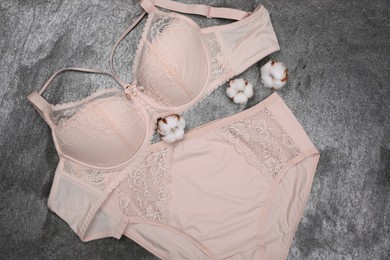 Photo of Elegant beige plus size women's underwear and cotton flowers on grey background, flat lay