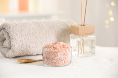 Photo of Spa composition. Sea salt, towel and reed air freshener on soft white surface
