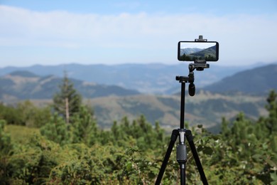 Photo of Taking video with modern phone on tripod in mountains